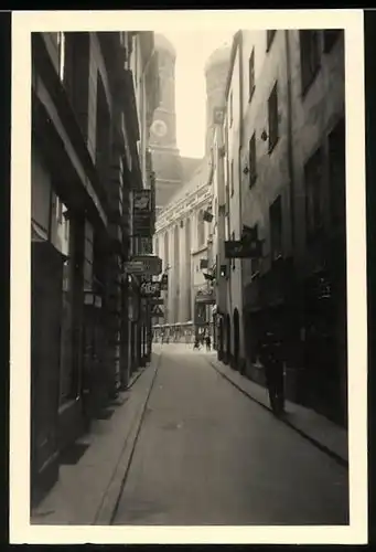 Fotografie unbekannter Fotograf, Ansicht München, Altstadt-Gasse mit Ladengeschäften und Blick zur Frauenkirche 1940