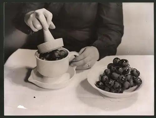 Fotografie Hausfrau benutzt neue Saftpresse für Trauben 1938
