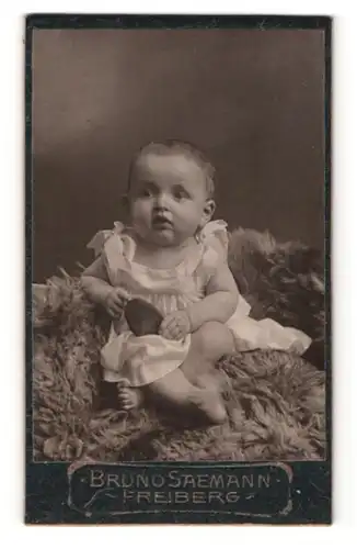 Fotografie Bruno Saemann, Freiberg, Portrait süsses Kleinkind im Hemdchen auf Fell sitzend