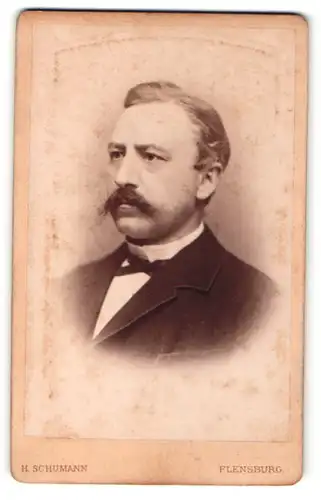 Fotografie H. Schumann, Flensburg, Portrait elegant gekleideter Herr mit Schnurrbart