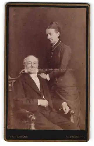 Fotografie H. Schumann, Flensburg, Portrait elegant gekleidetes Paar