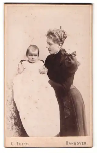 Fotografie C. Thies, Hannover, Portrait junge Dame im eleganten Kleid hält Baby am Arm