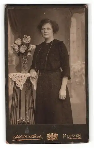 Fotografie Carl Beste, Minden i / W., Portrait bürgerliche Dame lehnt am Tisch mit Blumenvase