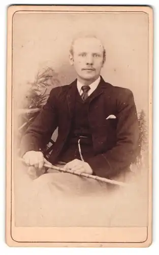 Fotografie H. G. Downes, Birmingham, Portrait sitzender Herr in eleganter Kleidung mit Stock