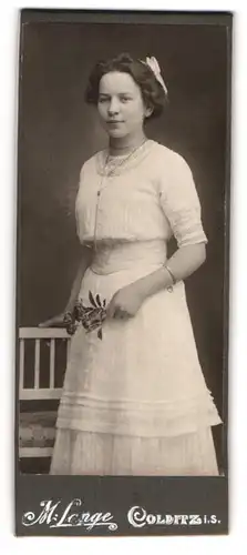 Fotografie M. Lange, Colditz i. S., Junge hübsche Frau in weissem Kleid mit breitem Bund und Rosen in der Hand