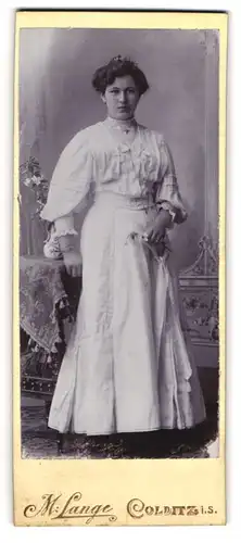 Fotografie M. Lange, Colditz i. S., Junge Frau in weissem langen Kleid mit Armband und Schmuck im Haar
