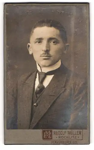 Fotografie Rudolf Müller, Rochlitz, Junger Mann mit kurzem Oberlippenbart in dunklem Anzug und Krawatte