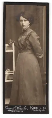 Fotografie Ernst Leube, Rochlitz, Elisabethplatz, Ernstschauende junge Dame in tailliertem Kleid mit langer Kette