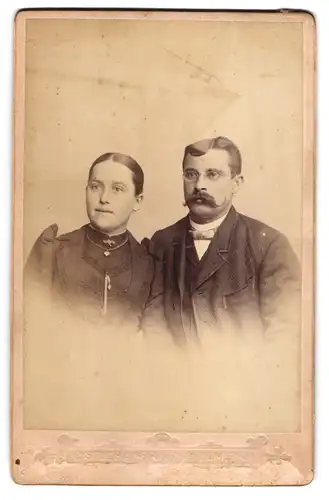 Fotografie C. Stichaner, Ulm, Ensingerstr. 4, Bürgerliches Paar in dunkler Kleidung mit silberner Kette und Fliege