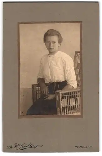Fotografie K. W. Schilling, Rochlitz i. Sa., Junge Dame in weisser Bluse und schwarzem Rock mit kleinen Augen am Lächeln