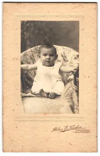 Fotografie E. Fischer, Zwenkau, Niedliches Baby mit grossem Kopf und erstauntem Blick in weissem Kleid