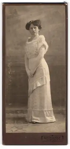 Fotografie Wilhelm Wolf, Wurzen, Nordstr. 7, Junge Dame in weissem Kleid mit Pelzsaumen schaut mit leichtem Silberblick