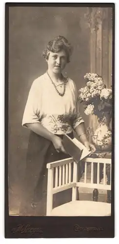 Fotografie M. Lange, Colditz i. S., Junge Frau mit leichtem Überbiss und breiter Perlenkette in weissem Kleid