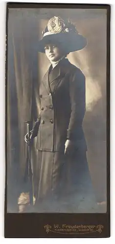 Fotografie W. Freudenberger, Niedersedlitz, Schulstr. 95, Junge Dame in schwarzem Anzugskleid mit grossem Hut und Blumen