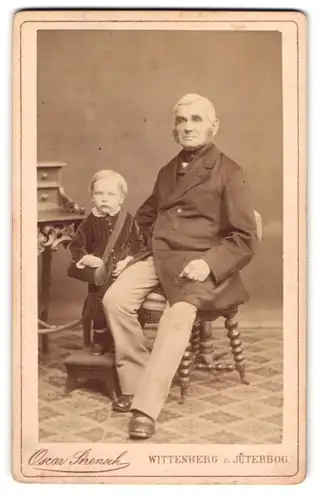 Fotografie Oscar Strensch, Wittenberg, Markt 14, Älterer Herr mit Backenbart posiert mit seinem Enkelkind
