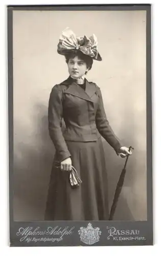 Fotografie Alphons Adolph, Passau, junge Dame Martha im dunklen Kleid mit Schleife am Hut und Regenschirm, 1901