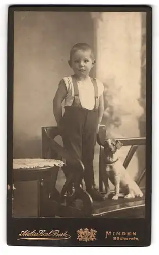 Fotografie Carl Beste, Minden i. W., junger Knabe in Latzhosen mit Hundestatue an der Seite