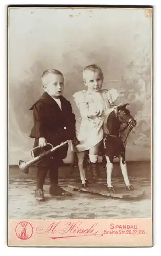 Fotografie M. Hirsch, Spandau, zwei Kleinkinder mit Blech Trompete und Schaukelpferd im Atelier