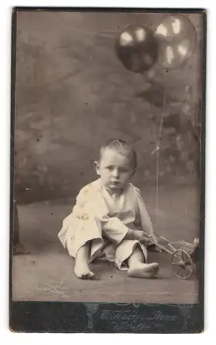 Fotografie O. Kneip, Bonn, junger Knabe spilet mit Spielzeug Kinderwagen, Lufballons