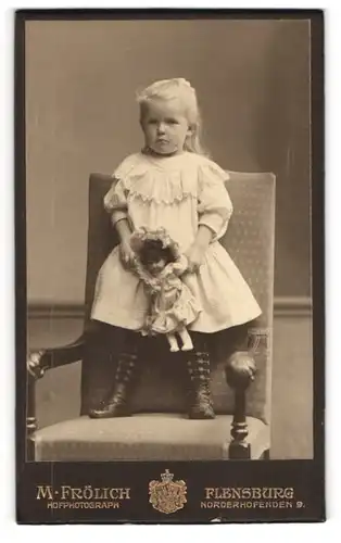 Fotografie M. Frölich, Flensburg, niedliches kleines Mädchen im Kleid mit Puppe in den Händen