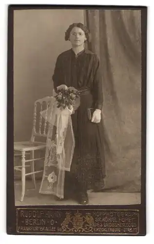 Fotografie Rudolf Hahn, Berlin, Mädchen im schwarzen Kleid mit Brille und Kommunions Blumenstrauss