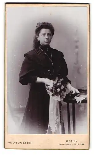 Fotografie Wilhelm Stein, Berlin, Mädchen im schwazen Kleid mit Blumenstraus zur konfirmation