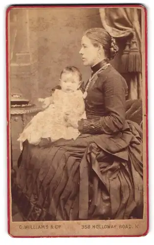 Fotografie C. Williams & Co., London, junge englische Mutter mit ihrer Tochter auf dem Schoss, Mutterglück