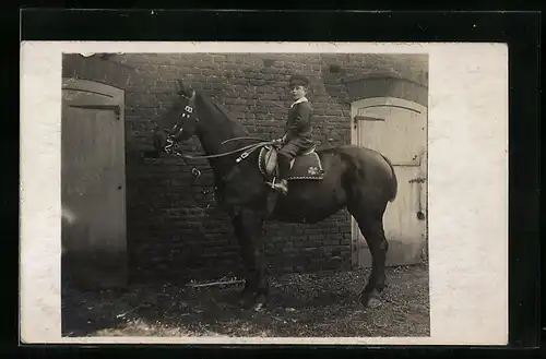 Foto-AK Knabe auf einem Reitpferd vor dem Stall