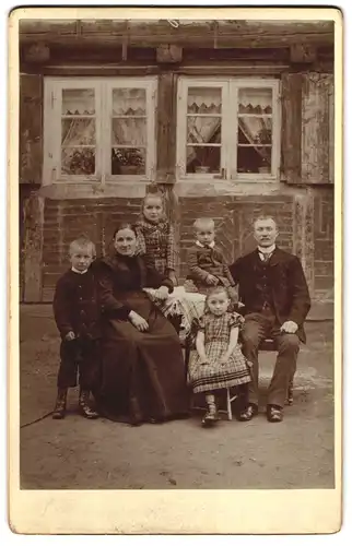 Fotografie unbekannter Fotograf und Ort, Mutter und Vater mit ihren vier Kindern vor dem Wohnhaus