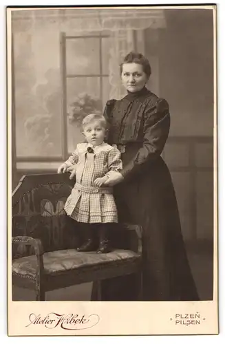 Fotografie Atelier Hrbek, Pilsen, Mutter im Kleid mit ihrem Sohn im karierten Kleid auf der Bank, Mutterglück