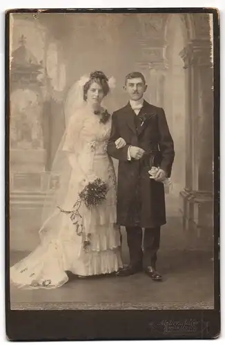 Fotografie Atelier Adler, Zwönitz i. Sa., junges Brautpaar im weissen Hochzeitskleid und im Anzug mit Chapeau Claque