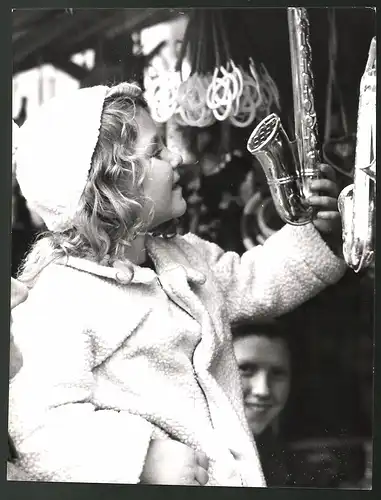 Fotografie Kleines Mädchen auf Weihnachtsmarkt mit Spielzeugsaxophon