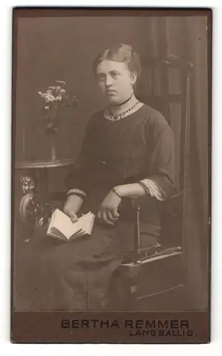 Fotografie Bertha Remmer, Langballig, Portrait sitzende Dame in modischer Kleidung mit Buch
