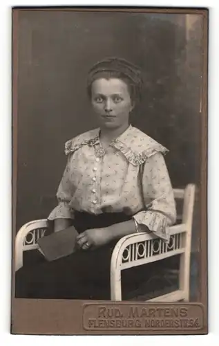 Fotografie Rud. Martens, Flensburg, Frau mit hochgesteckter Frisur und Buch in den Händen