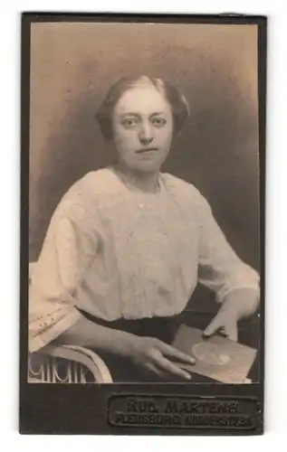 Fotografie Rud. Martens, Flensburg, Frau mit zurückgesteckter Frisur und Buch in den Händen