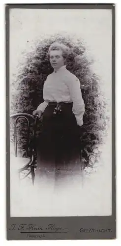 Fotografie J. F. Herm. Höge, Geesthacht, Frau in Bluse und Rock vor Gebüschen stehend