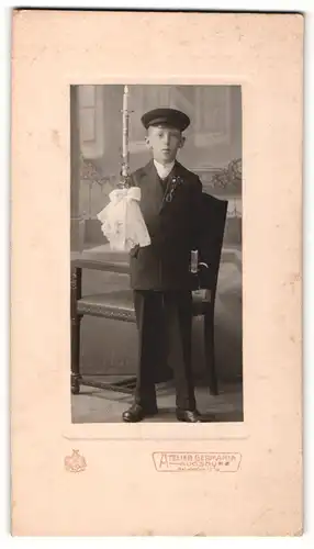 Fotografie Atelier Germania, Augsburg, Junge in Kommunionsanzug mit Kerze und Buch in den Händen