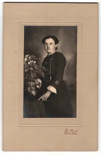 Fotografie A. Juul, Flensburg, Portrait junge Dame im schwarzen Kleid mit Blumenvase