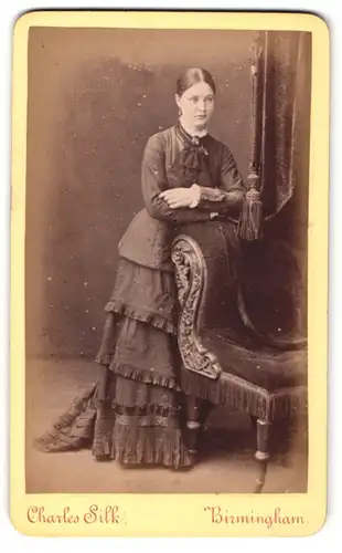 Fotografie Charles Silk, Birmingham, Portrait hübsch gekleidete Dame an Stuhl gelehnt