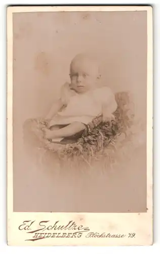 Fotografie Ed. Schultze, Heidelberg, Portrait süsses Baby im weissen Hemd mit nackigen Füssen