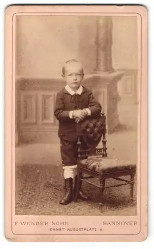Fotografie F. Wunder Sohn, Hannover, Portrait kleiner Junge in hübscher Kleidung an Stuhl gelehnt
