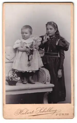Fotografie Hubert Schilling, Fürth, Portrait kleines Mädchen im hübschen Kleid und Kleinkind mit Puppe