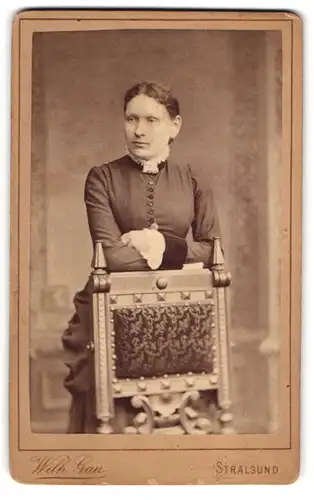 Fotografie Wilh. Gau, Stralsund, Böttcher Str. 9, Attraktive Dame mit Hochsteckfrisur lehnt sich lässig auf einen Stuhl
