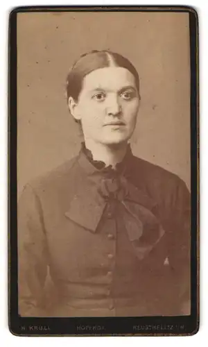 Fotografie H. Krull, Neu-Strelitz, Hübsche junge Frau mit Hochsteckfrisur und grosser Schleife am Kleid