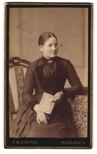 Fotografie F. W. Steffen, Friedland i. M., Hübsche junge Frau im eleganten Kleid und mit Buch in der Hand