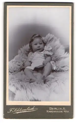 Fotografie F. Schloenbach, Berlin, Hasenheide 52 /53, Kleines süsses Mädchen im weissen Kleid auf einem Fell liegend