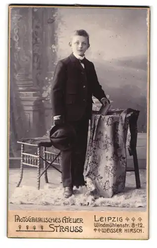 Fotografie Strauss, Leipzig, Windmühlenstr. 8, Junger Bursche im schwarzen Anzug mit Hut und Buch