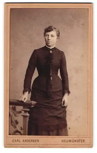 Fotografie Carl Andersen, Neumünster, Fabrik-Strasse, Junge Dame in schwarzem taillierten Kleid mit silberner Kette