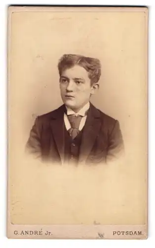Fotografie G. André Jr., Potsdam, Spandauer Str., Junger Bursche in schwarzem Anzug mit Krawatte und ernstem Blick