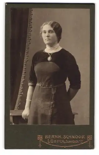 Fotografie Bernh. Schnoor, Lübeck, Sandstr. 17, Junge Dame in grauem Kleid mit breiter Halskette und weissem Kragen